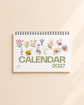 2027 floral desk calendar with botanical flower illustrations on a desktop
