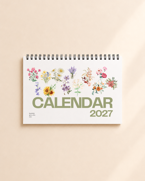 2027 floral desk calendar with botanical flower illustrations on a desktop